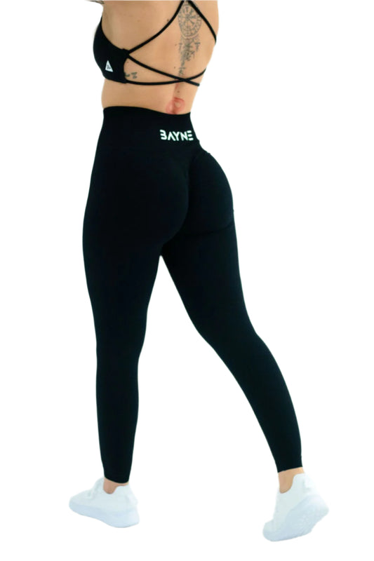 A rear view of a person wearing black seamless scrunch leggings and a matching sports bra.